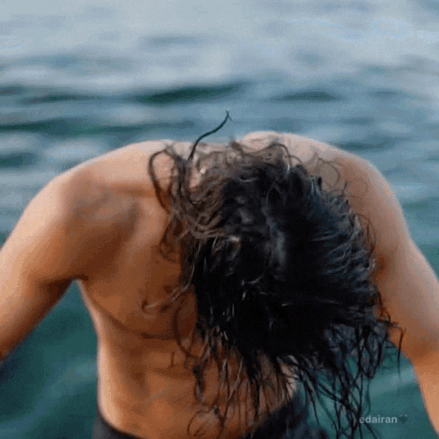 a shirtless man with long hair is standing in the water with the words edairan below him