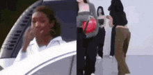 a woman is sitting in the driver 's seat of a car and a group of people are walking behind her .