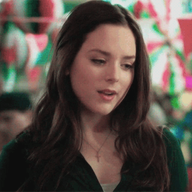 a woman wearing a black jacket and a cross necklace