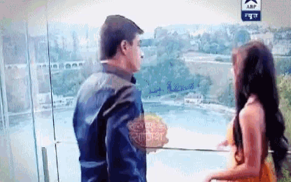 a man and a woman are standing on a balcony with the abp logo on the bottom right