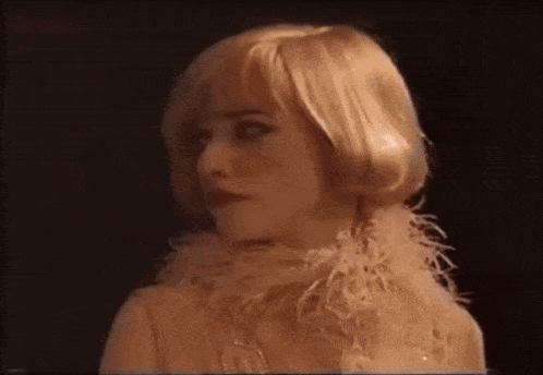 a woman with blonde hair is wearing a feathered scarf around her neck