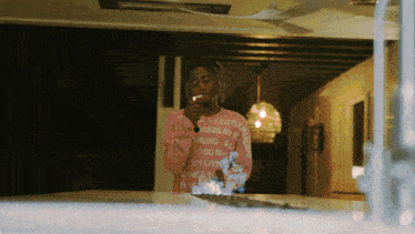 a woman wearing a pink sweater that says " my little darling " is smoking a cigarette