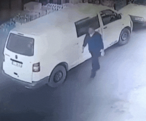 a man is standing next to a white van on a street .