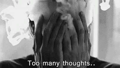 a black and white photo of a person covering their face with their hands and smoke coming out of their mouth .