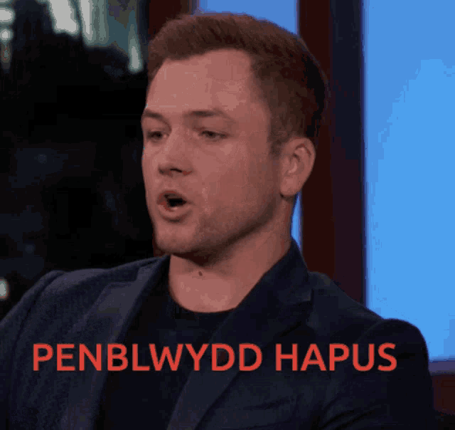 a man in a suit says penblwydd hapus in red