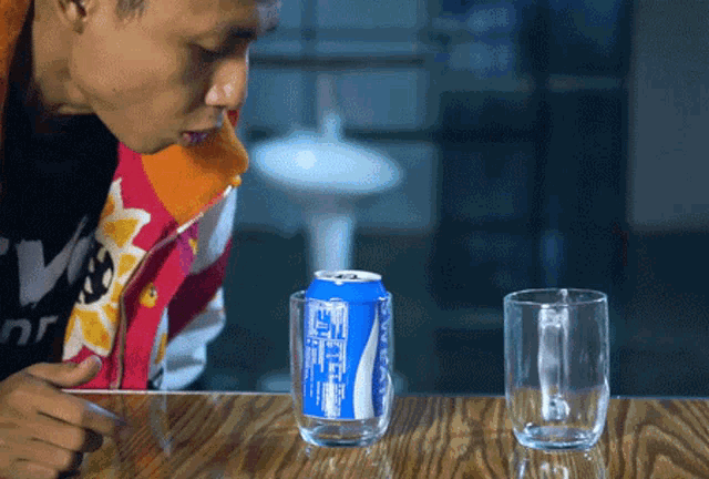a can of coca cola sits on a wooden table next to a glass