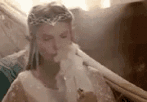 a woman in a white dress is smoking a cigarette while sitting in a hammock .