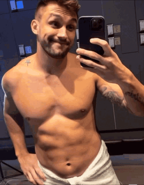 a shirtless man takes a selfie with his phone