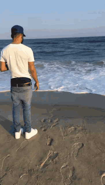 a man standing on a beach looking out to the ocean