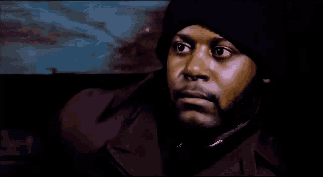 a close up of a man 's face with a purple jacket and a blue hat
