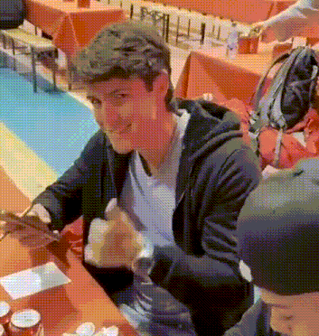 a man in a black hoodie is sitting at a table with other people .
