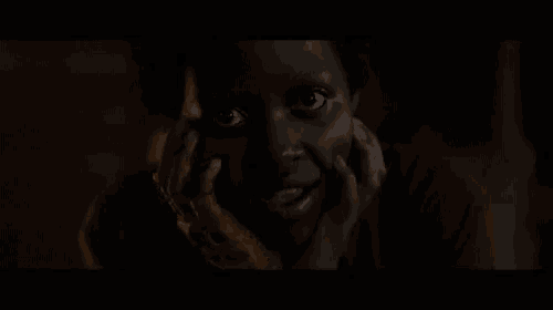 a close up of a person 's face in the dark with their hands on their face .