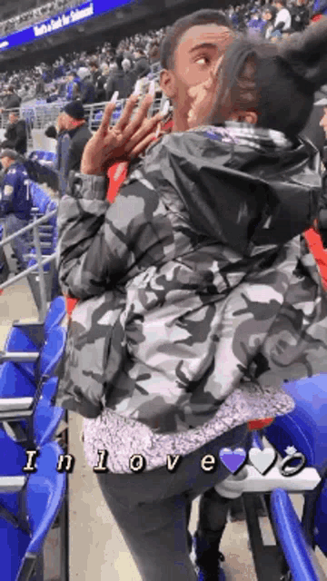 a man and a woman are kissing in the stands at a sports game .