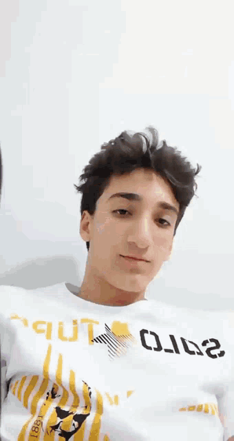 a young man is wearing a white shirt with the word out on the front