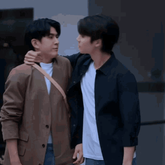 two men are standing next to each other and one of them is hugging the other