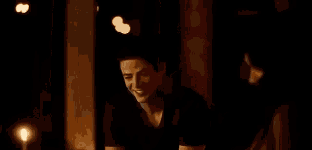 a woman is sitting in a dark room with candles and a man standing behind her .