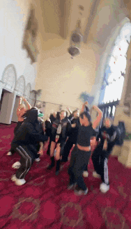 a group of people are dancing on a red rug in a church .
