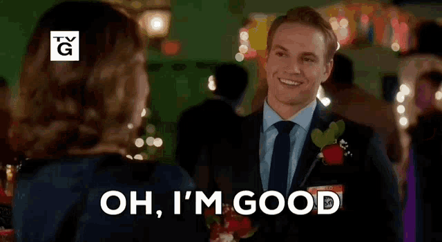 a man in a suit and tie is holding a rose and says oh i 'm good .