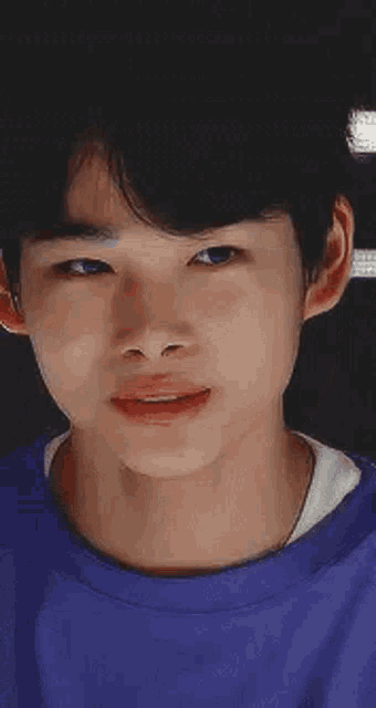 a close up of a young man 's face wearing a blue shirt .
