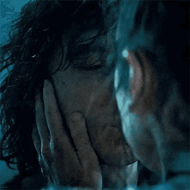 a close up of a man covering his face with his hand in the water .
