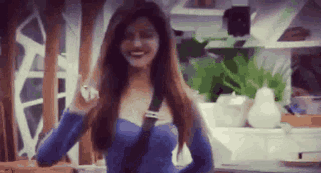 a woman in a blue dress is standing in a room with a blurred background .