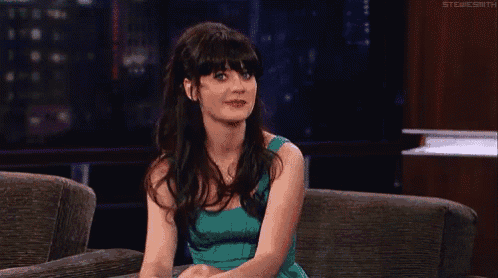 a woman in a blue dress is sitting on a couch with her legs crossed .