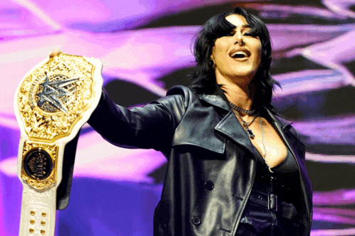 a woman in a leather jacket is holding a wrestling belt