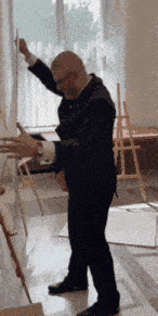a man in a suit is standing in front of an easel with his arms outstretched