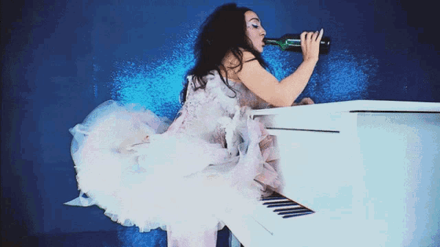 a woman in a white dress is drinking from a bottle