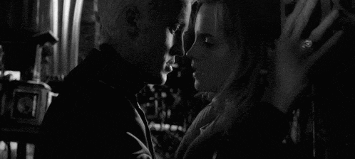 a black and white photo of a man and a woman looking into each other 's eyes .