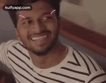 a man in a striped shirt is smiling and making a funny face .