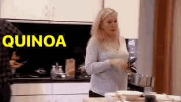 a woman is standing in a kitchen with the word quinoa written on the wall behind her