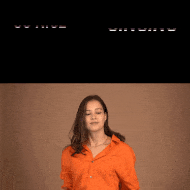 a woman in an orange shirt is dancing in front of a black screen that says singing