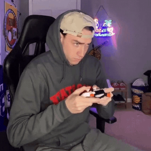 a man wearing a hoodie and hat is playing a video game with a controller