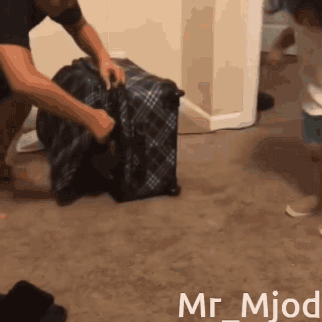 a man is packing a suitcase with the name mr_mjod written on the bottom