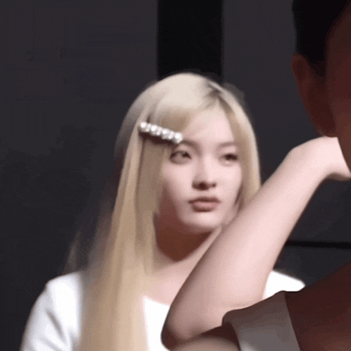 a woman with long blonde hair has a pearl hair clip on her head