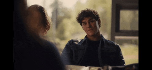 a man and a woman are sitting at a table and talking to each other