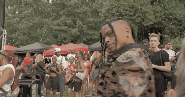 a man with braids stands in front of a crowd of people