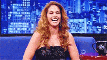a woman in a black dress is laughing on a couch