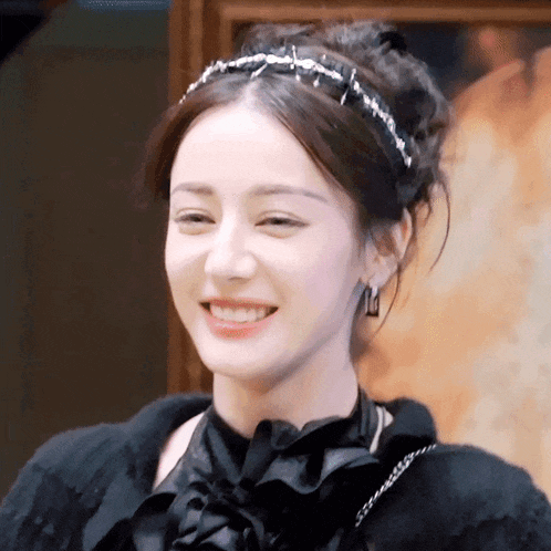 a woman wearing a headband and earrings is smiling .