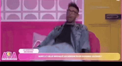 a man is sitting on a pink couch with a sign that says aja on it
