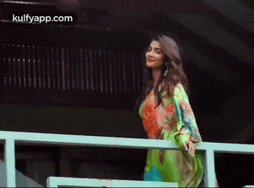 a woman in a green dress is standing on a railing .