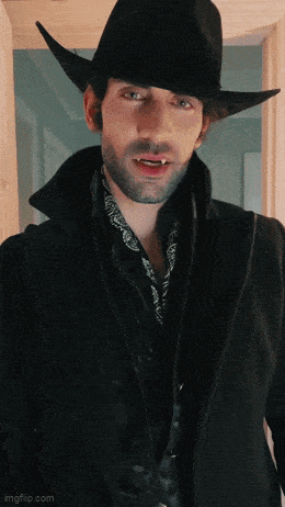 a man wearing a cowboy hat and a black coat is standing in a doorway