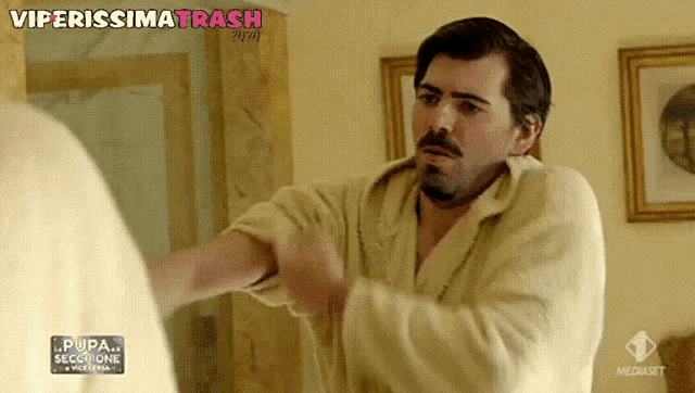 a man in a bathrobe is looking at himself in a mirror with the words viperissima trash written above him