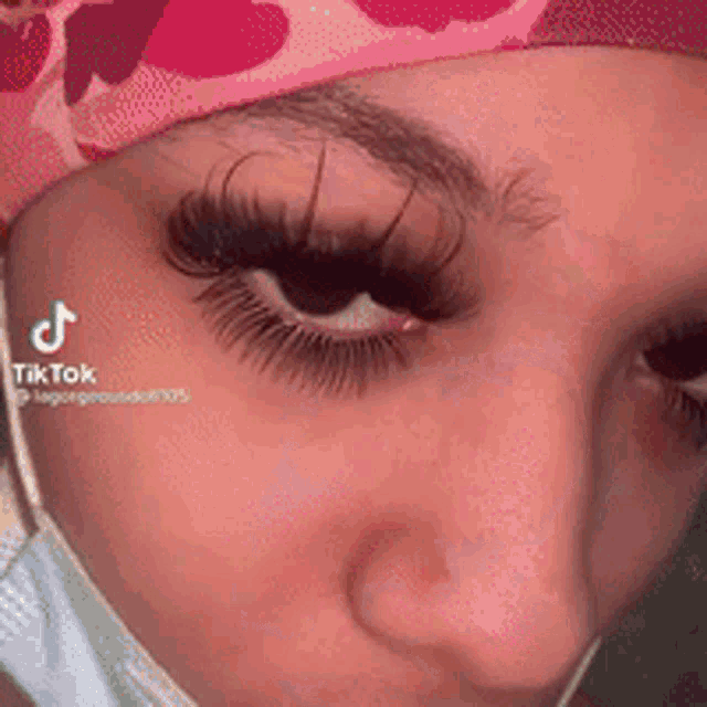 a close up of a woman 's face with a mask and a pink hat .