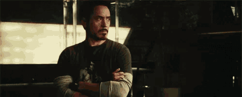 a man is standing with his arms crossed in a dark room .