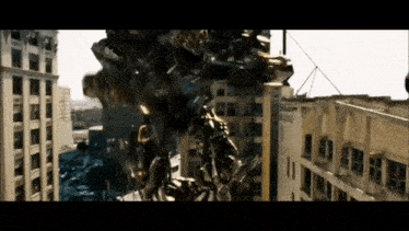 a robot is flying through the air in front of a building in a city .
