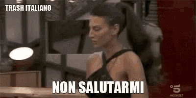 a woman is standing in front of a mirror with the words `` trash italiano non salutarmi '' written on the screen .