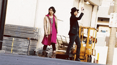 a man and a woman are walking down a street next to a forklift .
