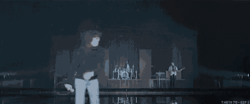a man is dancing on a stage in front of a band playing instruments .